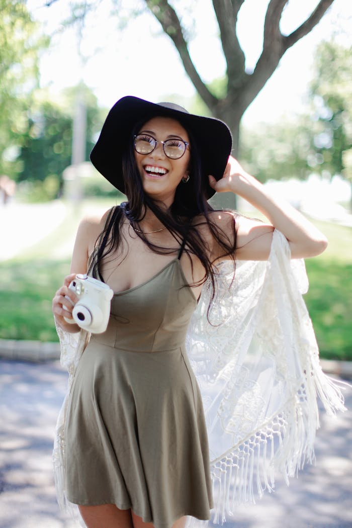 our-story Cheerful woman in a boho dress with a camera enjoying a sunny day outdoors.